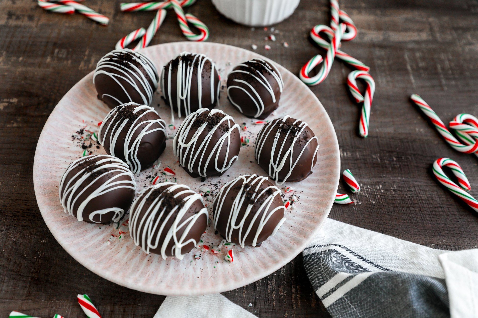 Holiday treats: a white platter covered in Fody's Chocolate Peppermint Truffles, surrounded by small green-and-red candy canes.