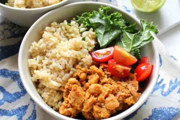 Smiling woman with shoulder-length wavy blonde hair wearing a black top, laughing joyfully in a bright indoor space with natural light.