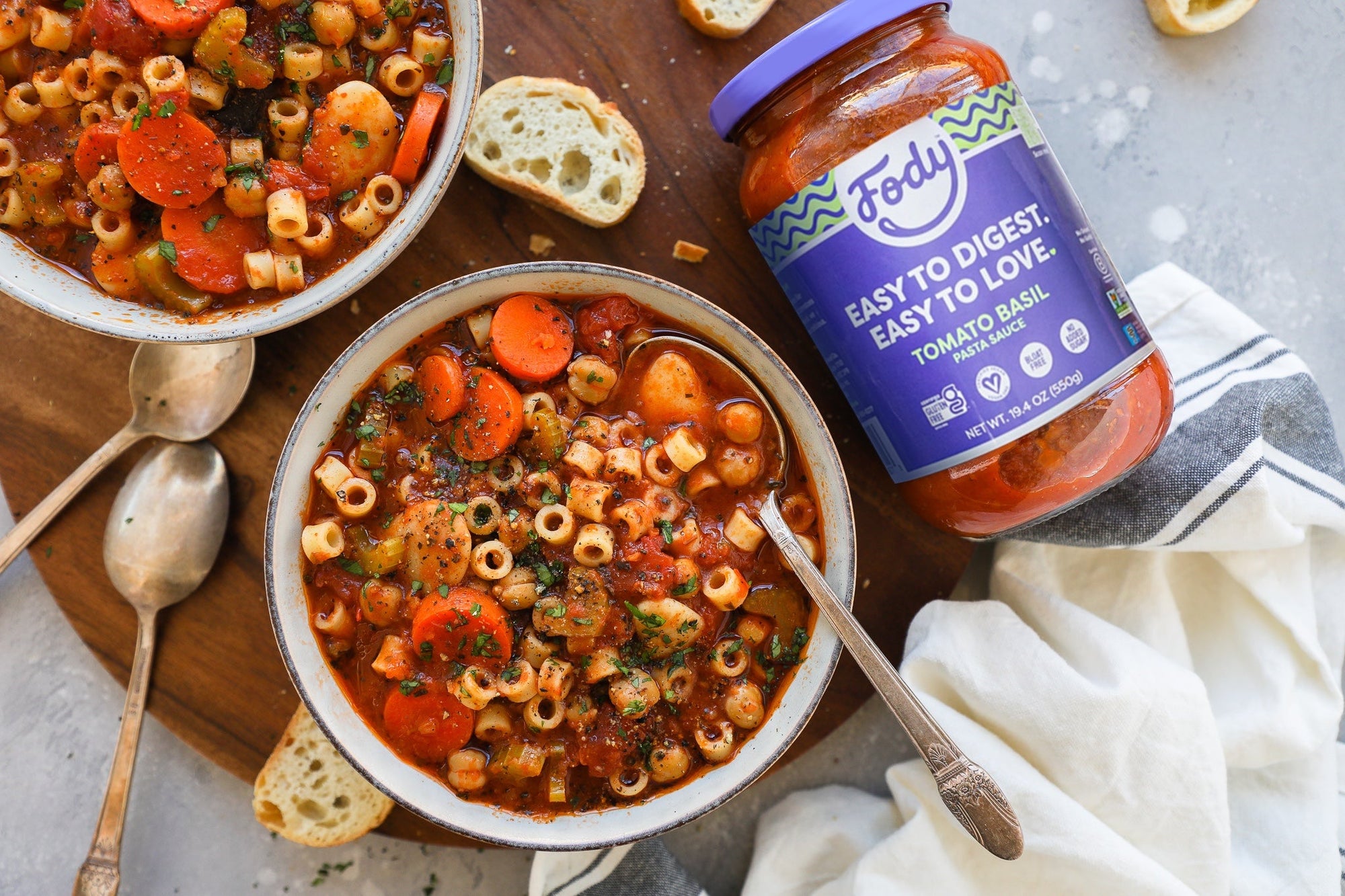 Two bowls of bloat-free pasta e fagioli laid out beside a jar of Fody's vegan bolognese.