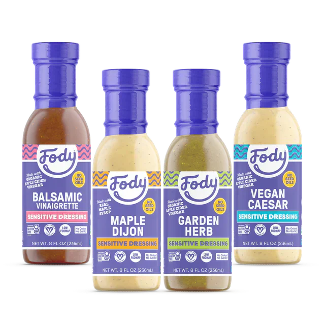  Four bottles of Fody Sensitive Dressings—Balsamic Vinaigrette, Maple Dijon, Garden Herb, and Vegan Caesar—made with apple cider vinegar and no seed oils.