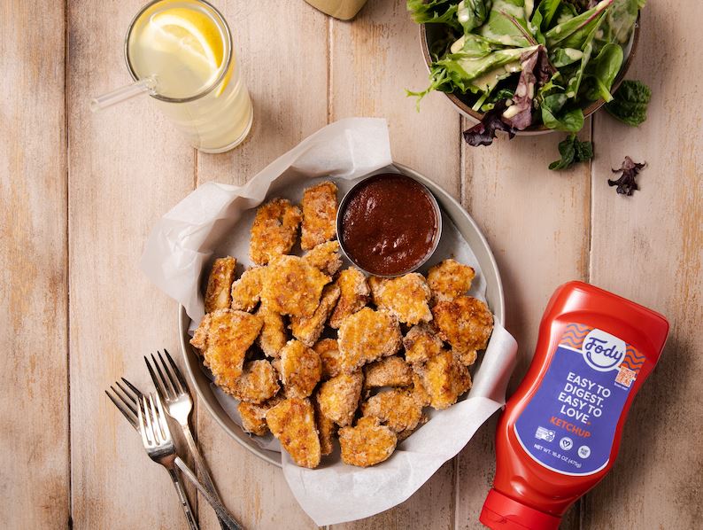 An image of Fody’s gluten free homemade chicken nuggets on a tray with a dipping sauce of zesty ketchup on the side.