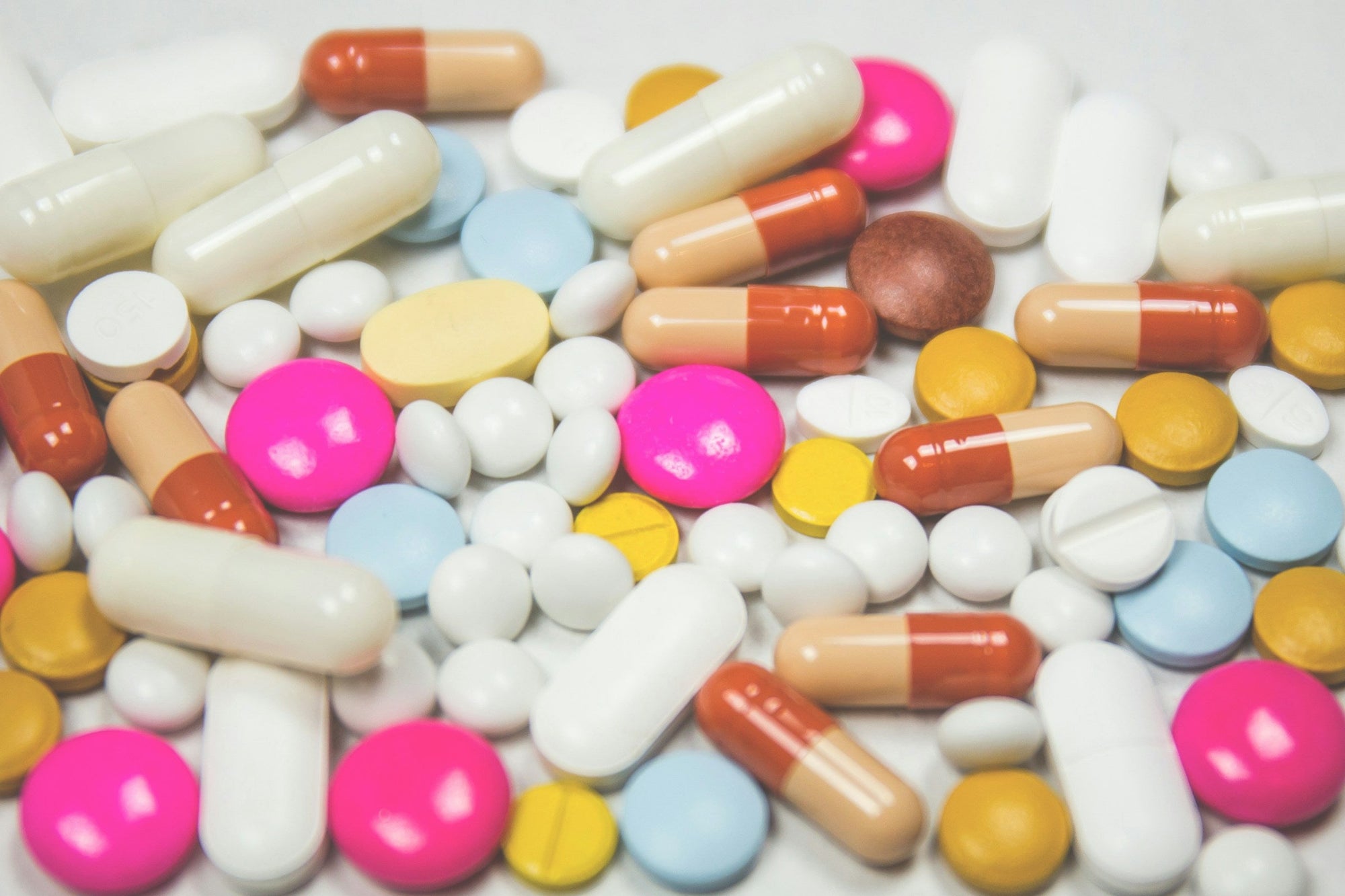 An assortment of colourful capsules and tablets spread across a white surface, representing the gut health supplement categories compared in a Canadian IBS supplement guide.