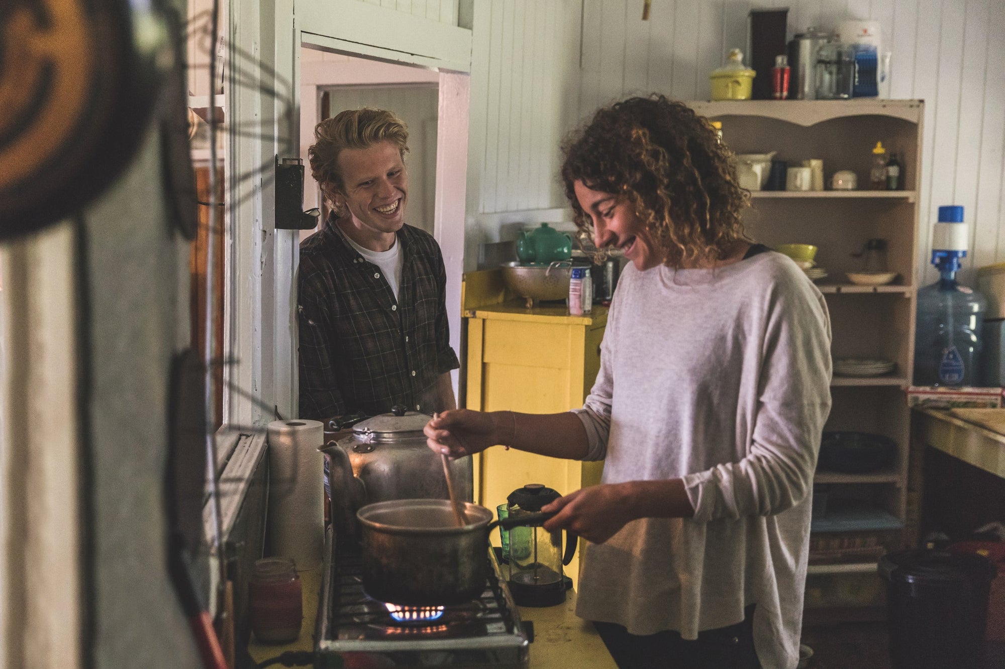 Image: A young couple preparing gut healthy comfort food in a cozy kitchen and laughing together.
