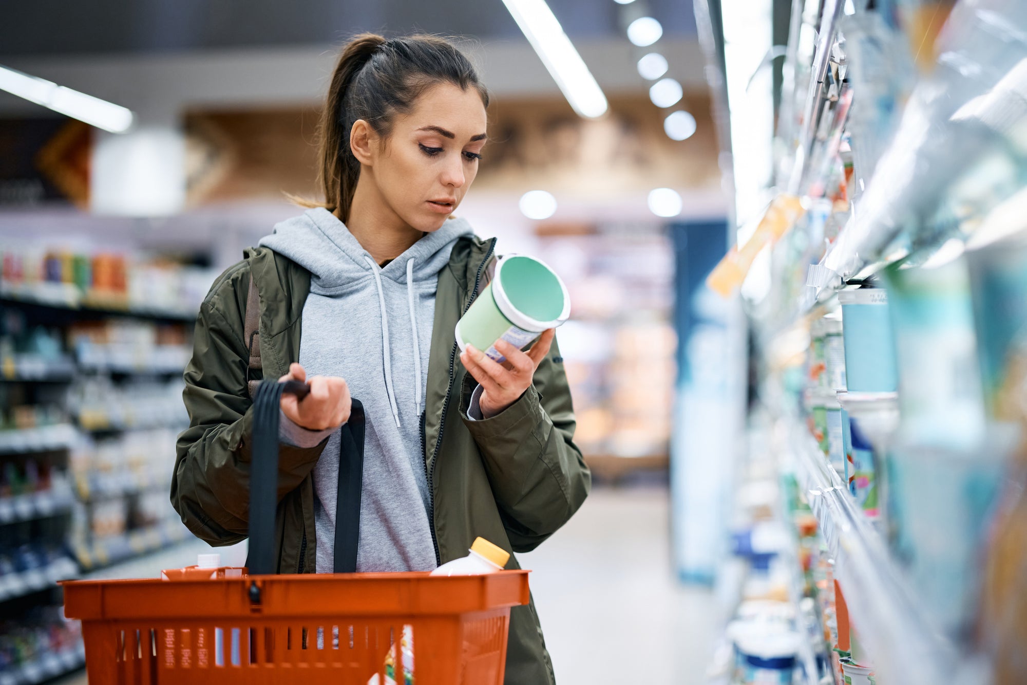 A young woman reads ingredient lists and nutrition information as she selects an item at the grocery store.