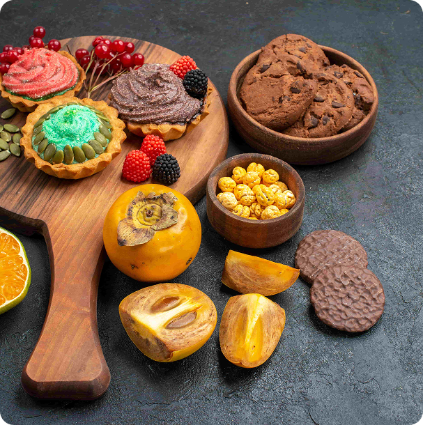 Whole and halved orange persimmons on a wooden cutting board against a deep blue backdrop, a bright seasonal fruit display from above