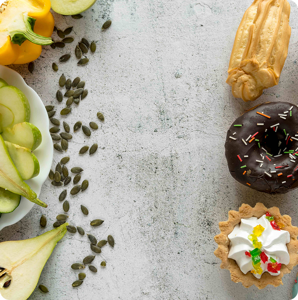 Flat lay of green foods on grey stone, with kiwi slices, avocado halves, leafy greens and other fresh produce arranged in loose rows
