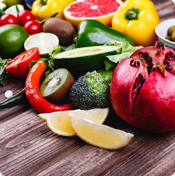 Overhead spread of whole foods, including fish, citrus, nuts, berries and leafy greens, arranged around a blank white card on a wooden table