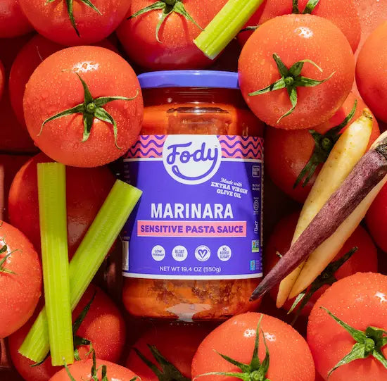 Fody Marinara Pasta Sauce jar among fresh tomatoes, celery and carrots, the simple ingredients in pasta sauce made without onion or garlic